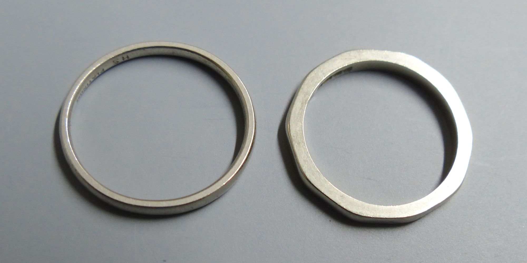 An 18ct gold decagonal wedding band (worn), size K, 2.9 grams and a white metal wedding band stamped Platinum, size M, 2.7 grams.